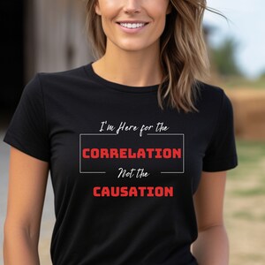 Op de afbeelding: Zwart T-shirt met de tekst "I'm Here for the CORRELATION Not the CAUSATION" in rood.