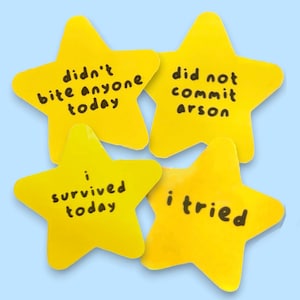 May include: Four yellow star-shaped stickers with black text. The stickers read: "didn't bite anyone today", "did not commit arson", "i survived today", and "i tried". The stickers are on a light blue background.