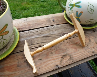 May include: A wooden yarn swift with a natural finish. The swift is lying on a wooden surface.