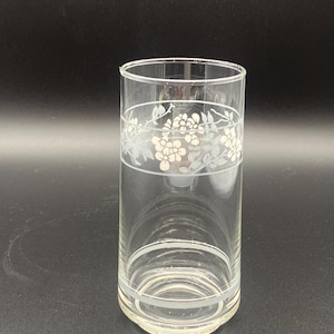 May include: A clear glass drinking glass with a white floral design around the middle.