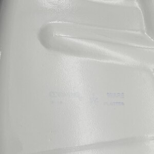 Puede incluir: Primer plano de un contenedor de pl&aacute;stico blanco con el texto "Wipe Plastic" impreso en tinta azul.