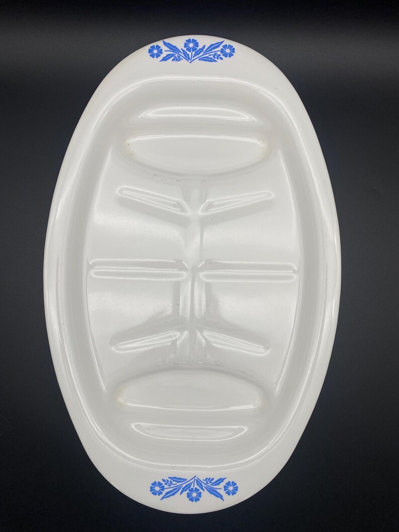 Puede incluir: Plato de servir ovalado blanco con un dise&ntilde;o floral azul alrededor del borde. El plato tiene cuatro secciones hundidas para servir comida.