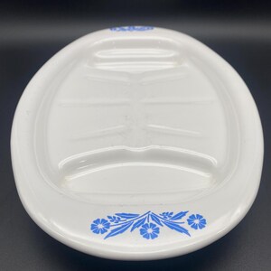 Puede incluir: Plato ovalado blanco para servir con un dise&ntilde;o floral azul alrededor del borde. El plato tiene tres secciones hundidas para servir.