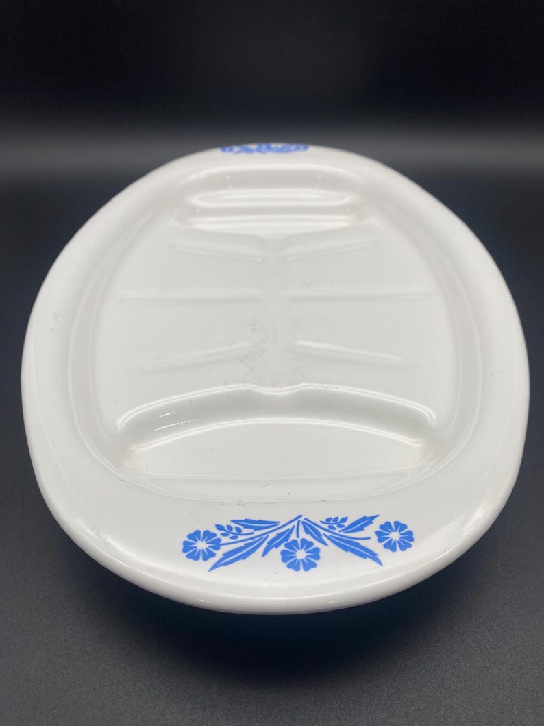 Puede incluir: Plato ovalado blanco para servir con un dise&ntilde;o floral azul alrededor del borde. El plato tiene tres secciones hundidas para servir.
