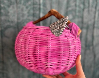 Wicker, bright basket in the shape of a cherry with a wooden handle and a decorative element in the form of a leaf