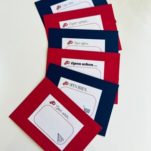 May include: Six red and blue envelopes with white labels. Each label has a whistle icon and the text "Open when..." followed by a blank space. The last envelope has a pizza icon.