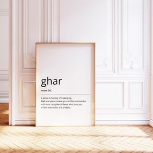 May include: A black and white printable wall art print with a gold frame. The print features the word "ghar" defined as a place and feeling of belonging.