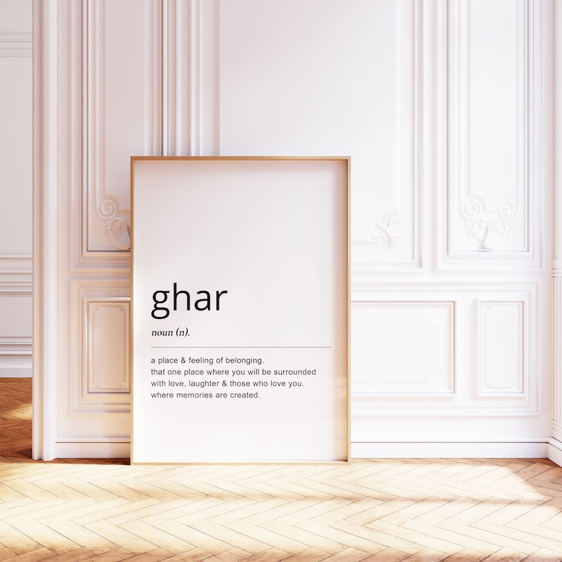 May include: A black and white printable wall art print with a gold frame. The print features the word "ghar" defined as a place and feeling of belonging.