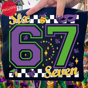 以下が含まれることがあります： 黒いトートバッグ。黄色、緑、紫で「Six 67 Seven」の文字が描かれています。デザインには、道化師のマスク、フルール・ド・リス、スターバーストが含まれています。バッグは人が持っています。