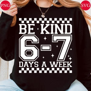 May include: Black sweatshirt featuring the white text "BE KIND 6-7 DAYS A WEEK". The design includes a checkered pattern, star accents, and bold, outlined numbers. The sweatshirt is a casual, everyday garment.