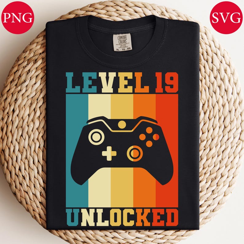 May include: Black t-shirt with a retro design featuring a video game controller and the text "LEVEL 19 UNLOCKED" in a colorful, vertical striped background. The shirt is made of a soft material and is suitable for casual wear.