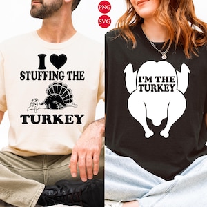 Puede incluir: Una camiseta color crema con texto negro que dice I heart stuffing the turkey y un gráfico de pavo, junto a una camiseta negra con texto blanco que dice I'm the turkey y una silueta de pavo blanca.
