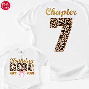 Può includere: Due magliette bianche con testo dorato e dettagli animalier. Una maglietta dice "Birthday GIRL EST. 2019" con un fiocco rosa. L'altra dice "Chapter 7". Le magliette sono probabilmente per una festa di compleanno.