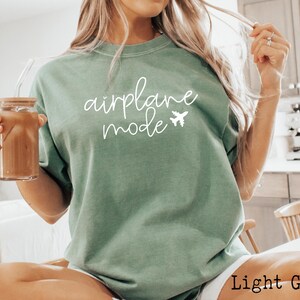 May include: A light green t-shirt with the text "airplane mode" in white lettering and a small airplane graphic.