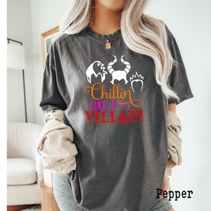 May include: A gray t-shirt with a white graphic of the Disney villain Maleficent with the text "Chillin' Like a Villain" in orange, pink, and red.