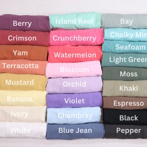 May include: A color chart of 18 different fabric swatches, each folded in half. The swatches are arranged in three columns of six swatches each. The colors include berry, crimson, yam, terracotta, mustard, banana, ivory, white, island reef, crunchberry, watermelon, blossom, orchid, violet, chambray, blue jean, bay, chalky mint, seafoam, light green, moss, khaki, espresso, black, and pepper.
