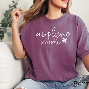 May include: A purple t-shirt with the text "airplane mode" in white script with a small airplane graphic.