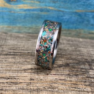 Pu&ograve; includere: Un anello d'argento con un'incisione macchiettata di verde, oro e marrone.