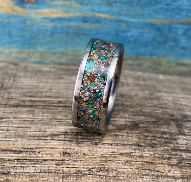 Pu&ograve; includere: Un anello d'argento con un'incisione macchiettata di verde, oro e marrone.