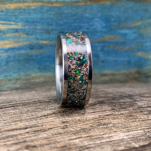 Pu&ograve; includere: Un anello d'argento con un'incisione verde, oro e bianca macchiettata.
