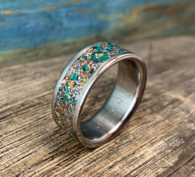 Pu&ograve; includere: Un anello d'argento con una fascia macchiata di verde, arancione e oro.