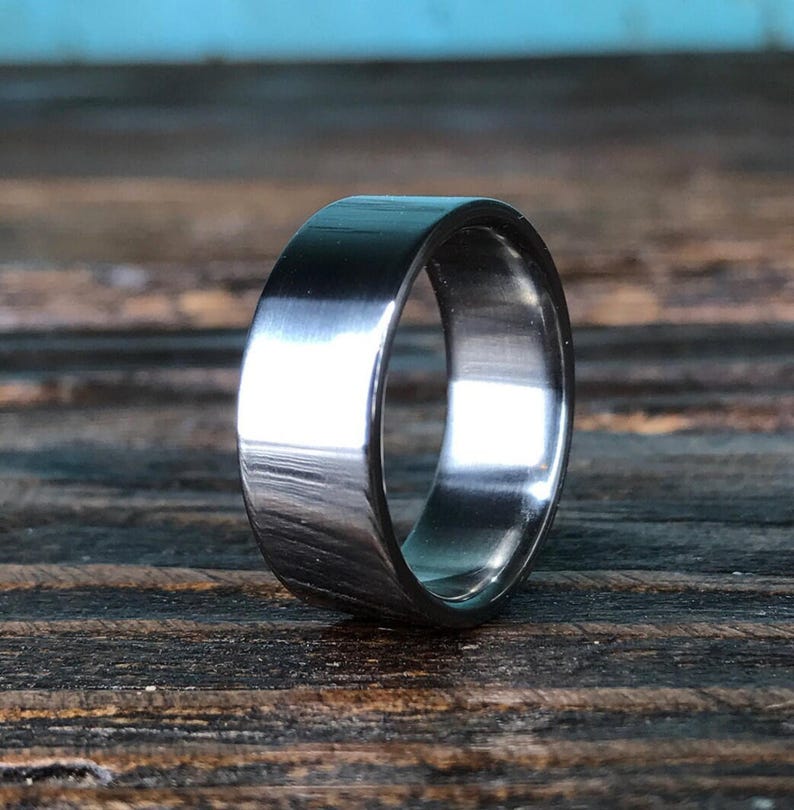 A metallic ring resting upright on a dark wooden surface.