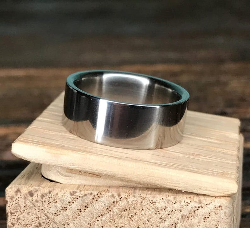 A silver metal ring resting on top of a small wooden box lid.