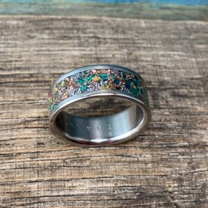 Pu&ograve; includere: Un anello d'argento con una fascia macchiata di verde, marrone e oro.