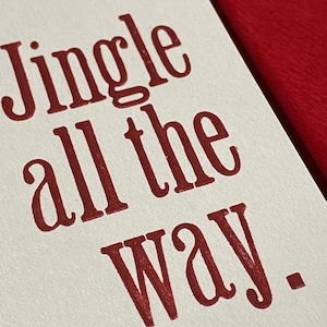 May include: A white card with the text "Jingle all the way." printed in red.