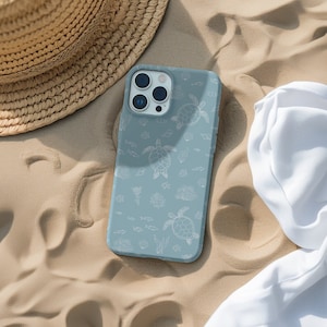 May include: A light blue phone case with a white outline of sea turtles and other sea life on a sandy background.