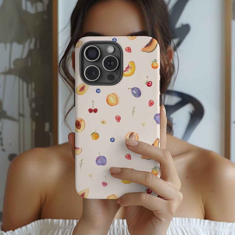 May include: A white phone case with a watercolor design of peaches, plums, cherries, and blueberries. The case has a camera lens cutout and a cutout for the phone's buttons.