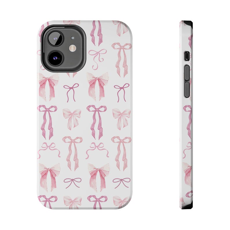 May include: A white phone case with a pink watercolor bow pattern. The case is designed for a smartphone with a camera bump.