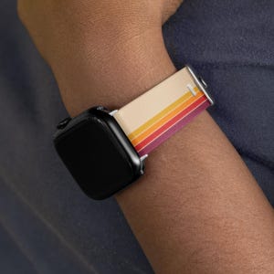 A person's wrist wearing a black smartwatch with a colorful striped band.