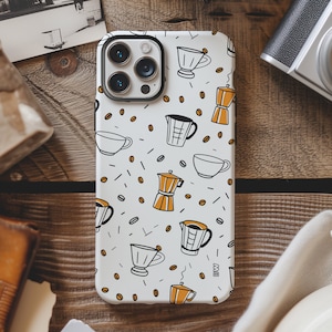May include: White iPhone case featuring a pattern of coffee cups, coffee pots, and coffee beans. The case has a black camera bump with three lenses.