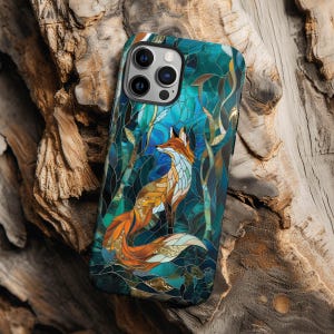 May include: A smartphone case featuring a stained glass style design of an orange fox surrounded by deep blue and teal geometric shapes. The case has a cutout for a triple camera lens system on the upper left corner and a smooth, glossy finish.