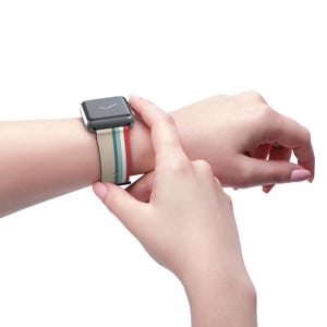 A person's hand is shown wearing a watch with a colorful band, with the watch face visible.