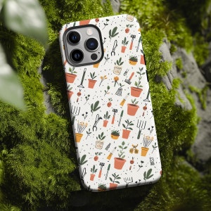 Op de afbeelding: Witte telefoonhoes met een patroon van tuingereedschap, planten en bloemen in tinten van groen, oranje en bruin.
