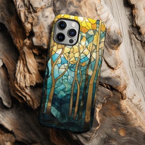May include: A phone case with a stained glass design featuring a forest scene with trees and a blue sky. The case is black and has a gold trim around the edges.