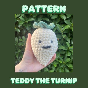 May include: A handmade, cream-coloured turnip toy with a smiling face and green leaves. The words "PATTERN" and "TEDDY THE TURNIP" are displayed in a green, textured font. The background is a dark green, leafy foliage.