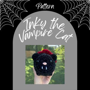 May include: A handmade black crochet cat with a red tuft of hair, a pink nose, and two white fangs. The cat is labeled "Inky the Vampire Cat" with the word "Pattern" above. The cat is held in a hand.