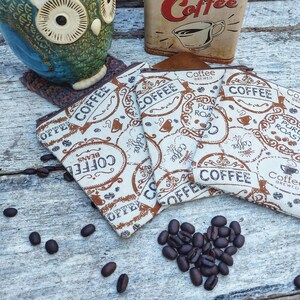 May include: Four beige fabric pouches with brown coffee bean designs and text that reads "Coffee", "Coffee Beans", "Pure Roast", and "Coffee Brewed".
