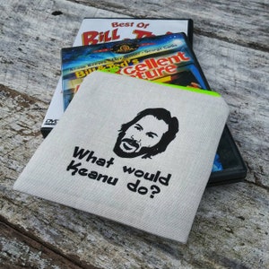 May include: A white canvas zippered pouch with a black and white image of Keanu Reeves and the text "What would Keanu do?" printed on it.