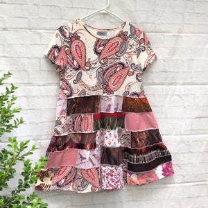 May include: A patchwork dress with a paisley print top and a multi-colored skirt. The skirt is made of different fabrics and has a layered look.