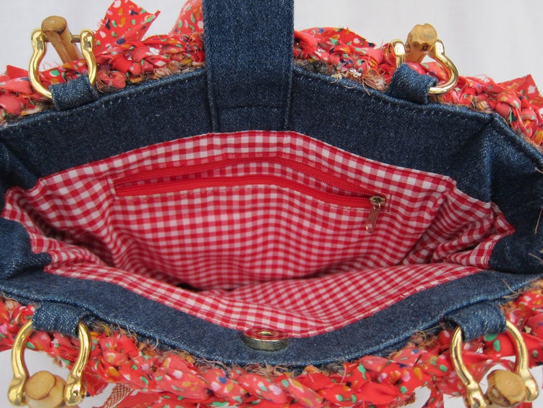 May include: A denim tote bag with a red and white gingham lining. The bag has a zippered pocket on the inside and two wooden handles.
