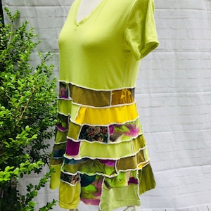 May include: A lime green t-shirt dress with a patchwork skirt made of different colored fabrics, including yellow, green, brown, and purple.