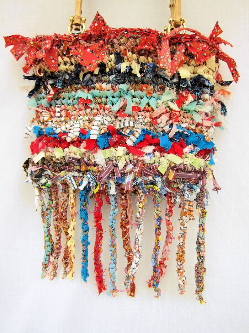May include: A colorful woven bag with a fringe made of fabric scraps. The bag has a red, blue, and white color scheme and is made with a variety of different fabrics.