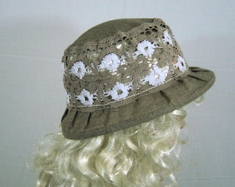 May include: A brown linen hat with a white crocheted trim. The hat has a wide brim and a slightly rounded crown.