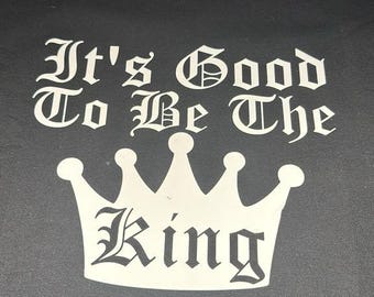 May include: Black crew neck t-shirt with the white text "It's Good To Be The King" above a white crown graphic. The text is in a gothic font. The shirt is made of a soft material.