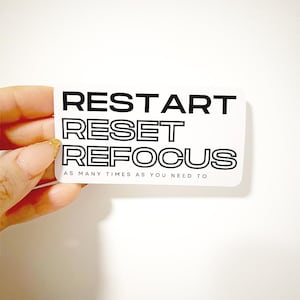 May include: White sticker with black text that reads "RESTART RESET REFOCUS AS MANY TIMES AS YOU NEED TO".