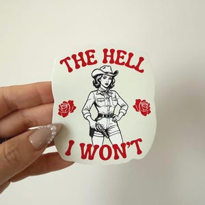 May include: A white sticker with a graphic of a cowgirl holding a gun, with the text "THE HELL I WON'T" in red. The cowgirl is wearing a cowboy hat, shirt, and shorts. Red roses are on either side of the cowgirl.